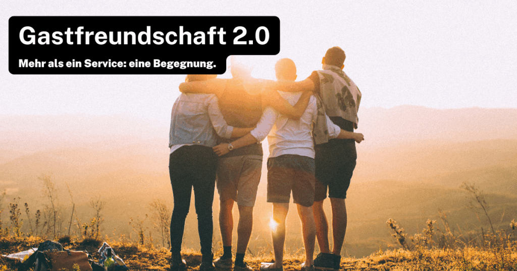 Vier Personen stehen auf einem Hügel und umarmen sich, während sie in den Sonnenuntergang blicken. Der Text „Gastfreundschaft 2.0“ und „Mehr als ein Service: eine Begegnung.“ ist oben links im Bild zu sehen.