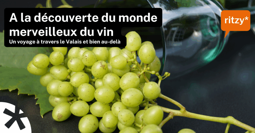 Grappe de raisins verts posée sur une feuille, avec un verre à vin renversé en arrière-plan. Texte en surimpression : “À la découverte du monde merveilleux du vin – Un voyage à travers le Valais et bien au-delà”. Logo ritzy* en orange.