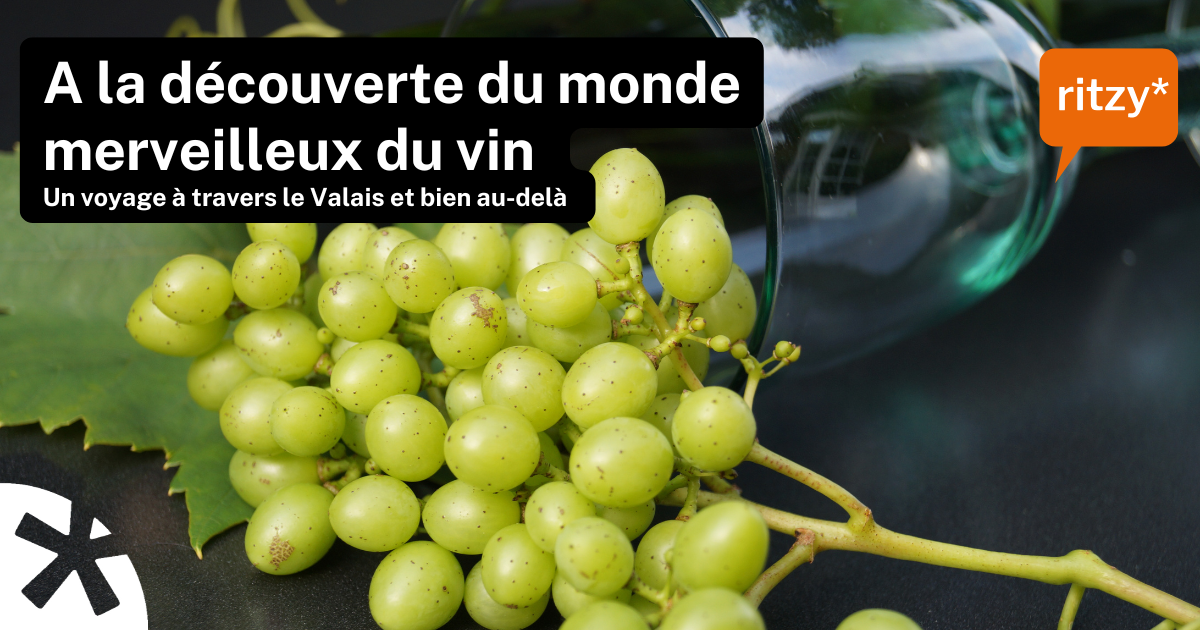 Grappe de raisins verts posée sur une feuille, avec un verre à vin renversé en arrière-plan. Texte en surimpression : “À la découverte du monde merveilleux du vin – Un voyage à travers le Valais et bien au-delà”. Logo ritzy* en orange.